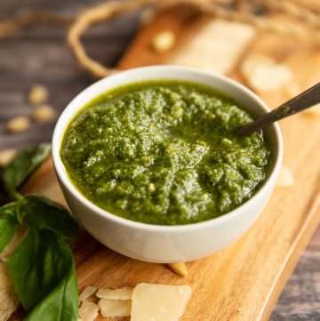 pesto in a small white pot on wooden chopping board