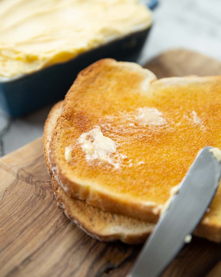 smudge of butter melting into slice of toast on chopping board