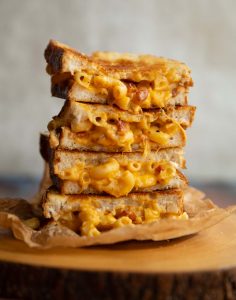 4 sandwich halves stacked on each other with mac and cheese spilling out