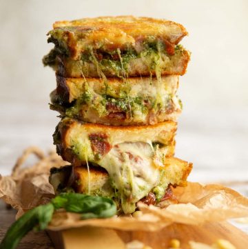 4 sandwich halves stacked on top of each other with pesto and cheese spilling out