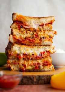 4 sandwich halves stacked on each other with cheese and filling spilling out