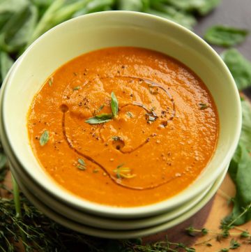 soup in green bowl with fresh basil and thyme blurred in background