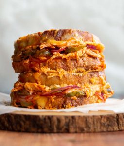 two grilled cheese stacked on each other on wooden block