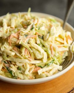 coleslaw served in white bowl with two silver forks