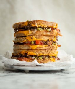 3 sandwich halves stacked on each other on small marble board