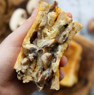 overhead shot of hand opening sandwich showing mushroom and cheese filling