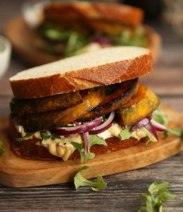 pumpkin sandwich on wooden board with another sandwich blurred in background