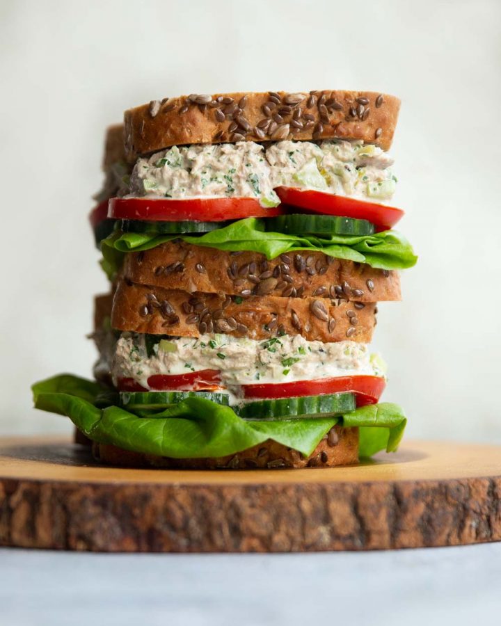 2 sandwiches stacked on each other on wooden board