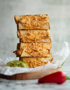 4 sandwich halves stacked on each other on small wooden board