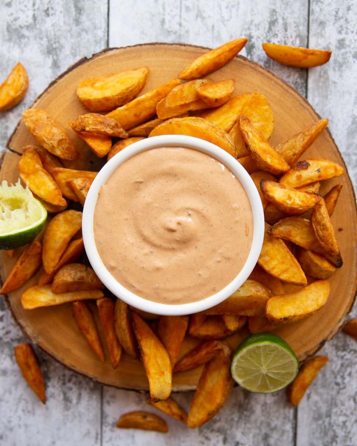 overhead shot of chipotle mayo in white pot surrounded by potato wedges