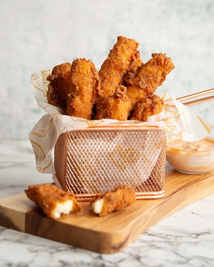 halloumi fries in small basket on wooden board with dip