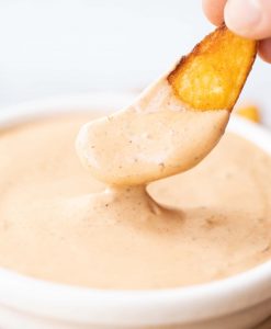 close up shot of potato wedge being dunked into pot of chipotle mayo