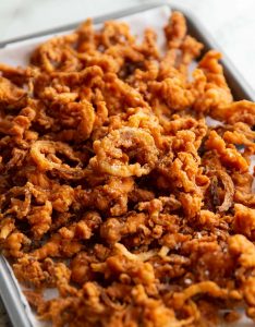 fried onions fresh out the fryer on baking tray