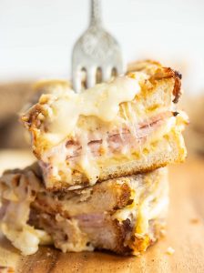 close up of quarter of croque monsieur with silver fork stabbing in showing filling