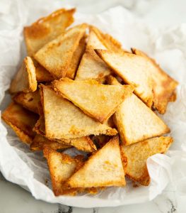 grilled cheese chips in crumpled parchment paper on marble backdrop