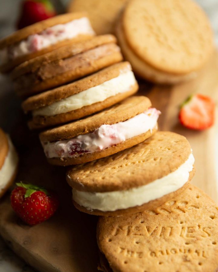 6 cheesecake sandwiches spread on wooden board with strawberries