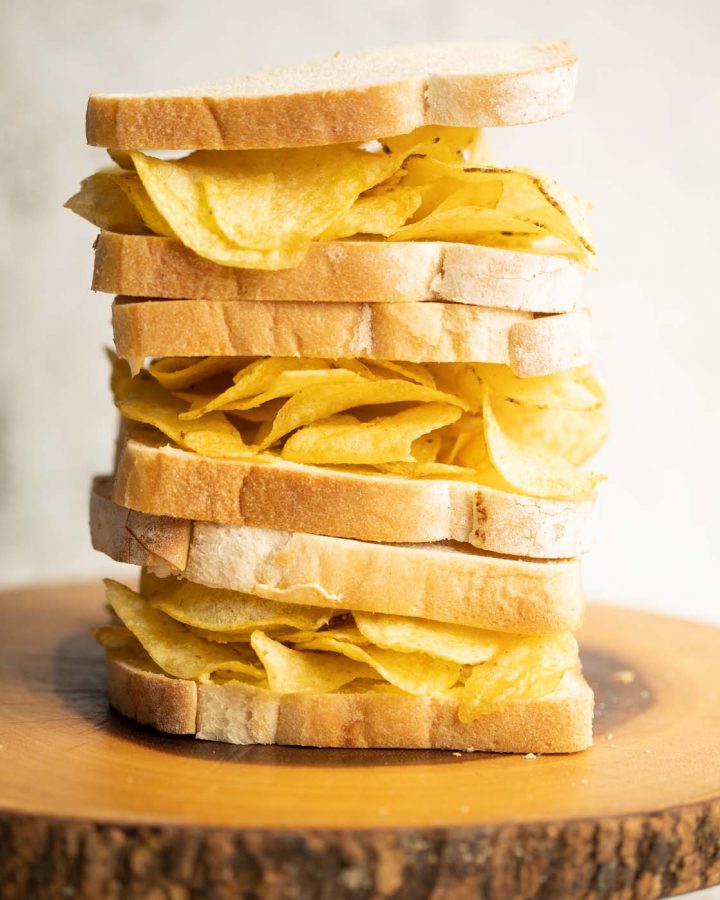3 crisp sandwiches stacked on each other on wooden board