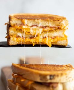 half of grilled cheese resting on black spatula with cheese dripping out