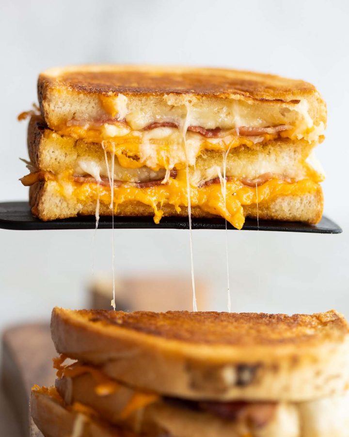 half of grilled cheese resting on black spatula with cheese dripping out