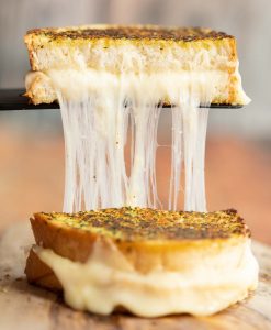 spatula lifting garlic bread grilled cheese with cheese dripping out