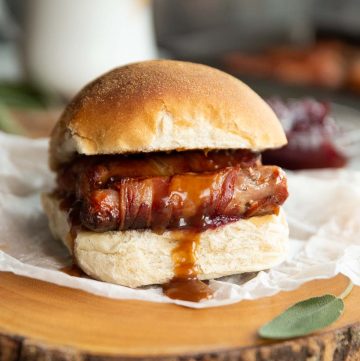 pigs in a blanket sandwich on wooden board with gravy dripping out