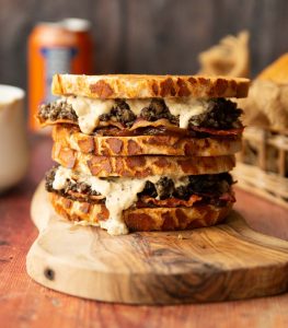 two haggis sandwiches stacked on each other on wooden board