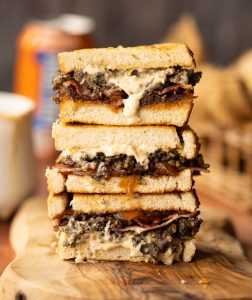3 haggis sandwiches stacked on each other on wooden board
