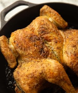 close up shot of cooked spatchcock chicken in large cast iron skillet