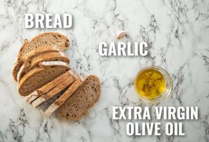 overhead shot of bread garlic and oil with text labels
