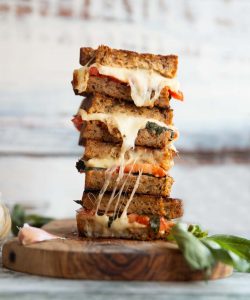 4 caprese sandwich halves stacked on each other with cheese dripping out