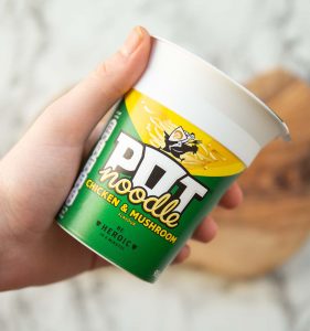 close up shot of hand holding chicken and mushroom pot noodle