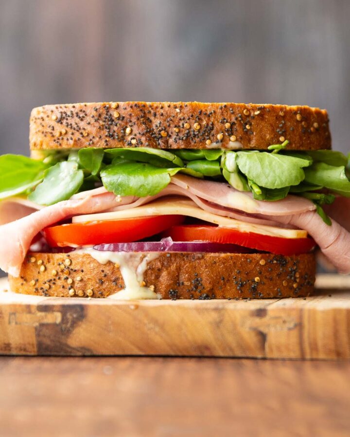 close up shot of ham sandwich on wooden board with wooden backdrop