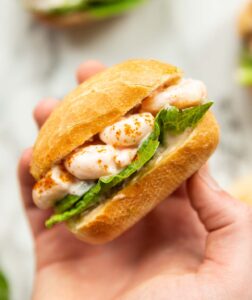 close up over head shot of hand holding prawn cocktail sandwich