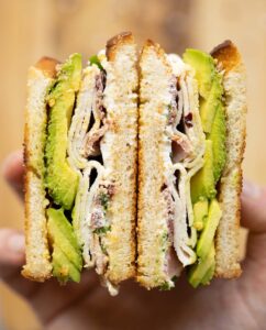 close up overhead shot of avocado turkey sandwich sliced in half showing filling