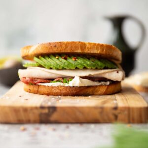 close up shot of turkey avocado sandwich on wooden board showing filling