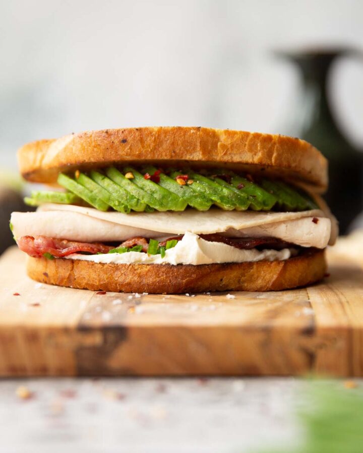 close up shot of turkey avocado sandwich on wooden board showing filling