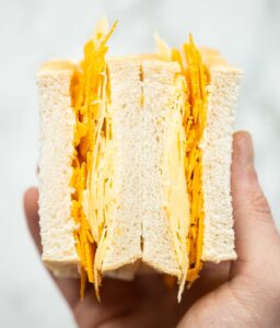 close up overhead shot of hand holding cheese sandwich showing filling
