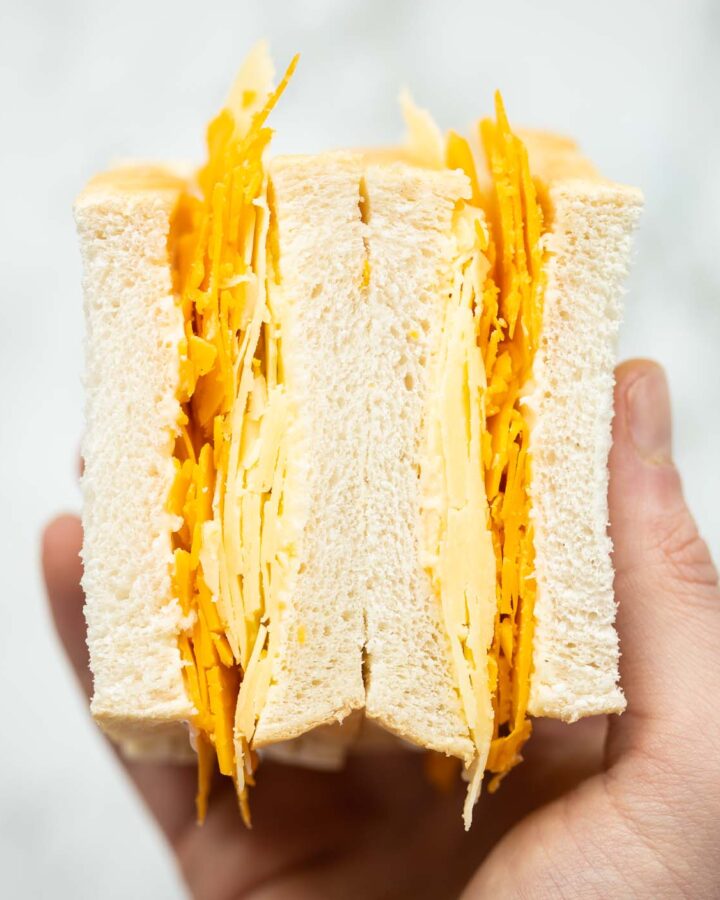 close up overhead shot of hand holding cheese sandwich showing filling