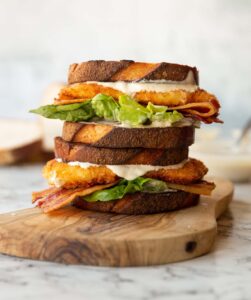2 chicken caesar sandwiches stacked on each other with bread and sauce blurred behind